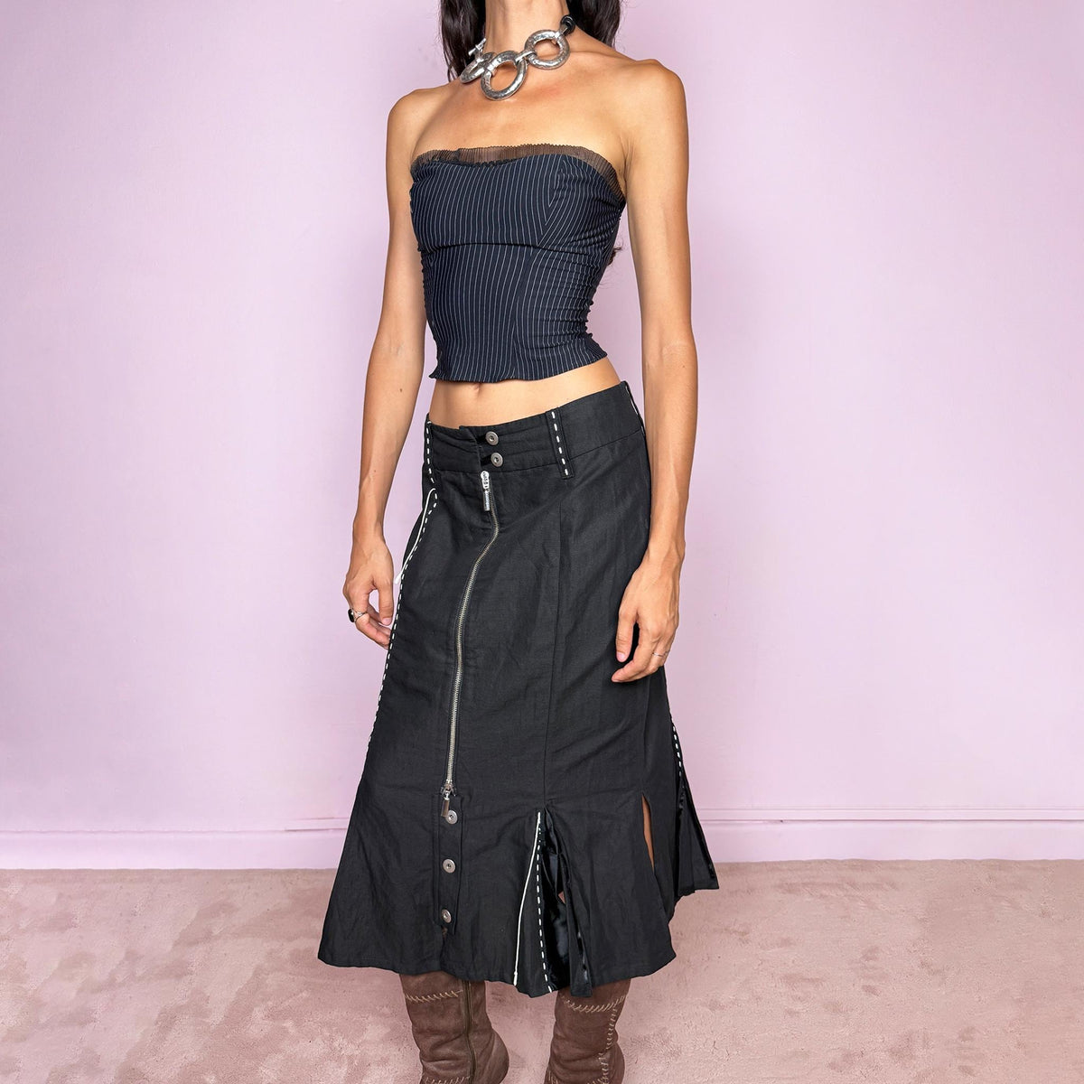 Vintage 2000s black midi skirt featuring an exposed full-length front zip, double-button waistband, and contrast white stitching throughout. The lower section opens into sculptural deconstructed panels with additional button and zip detailing, creating an asymmetric, utilitarian avant-garde feel. Can be worn high-waisted for size M or slightly lower on the waist for sizes S and XS. Non-stretch. Made in Holland by a Dutch brand from a structured blend of 52% cotton and 48% linen
