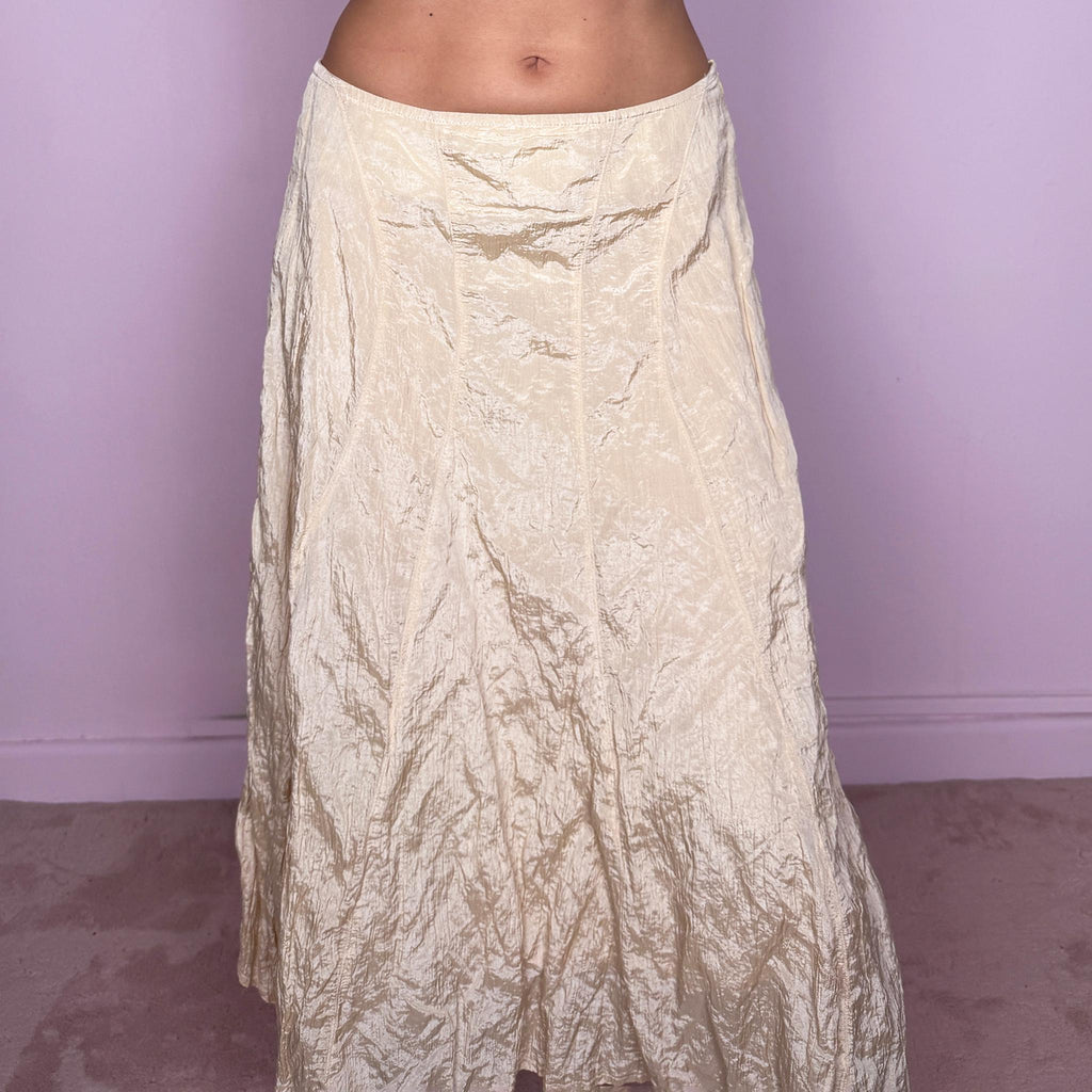 Vintage 2000s light cream-gold asymmetric midi skirt featuring a flared silhouette with an irregular handkerchief-style hem and a subtly crinkled, textured finish. Crafted from a structured, non-stretch blend of 53% polyamide, 32% cotton and 15% metallic fiber, with a 65% acetate and 35% viscose lining. Finished with a side zip closure. Can be worn mid-rise for size S or lower on the waist for size XS. From a German brand. Excellent vintage condition.