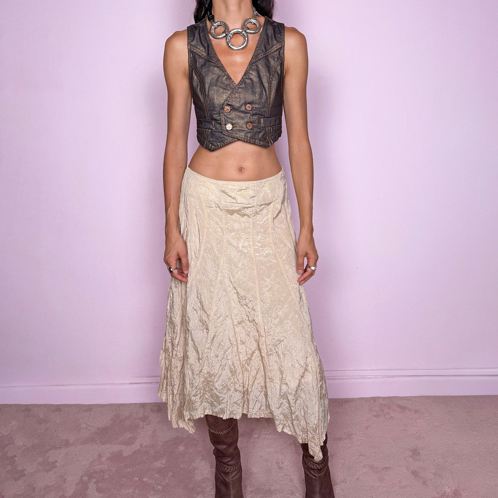 Vintage 2000s light cream-gold asymmetric midi skirt featuring a flared silhouette with an irregular handkerchief-style hem and a subtly crinkled, textured finish. Crafted from a structured, non-stretch blend of 53% polyamide, 32% cotton and 15% metallic fiber, with a 65% acetate and 35% viscose lining. Finished with a side zip closure. Can be worn mid-rise for size S or lower on the waist for size XS. From a German brand. Excellent vintage condition.