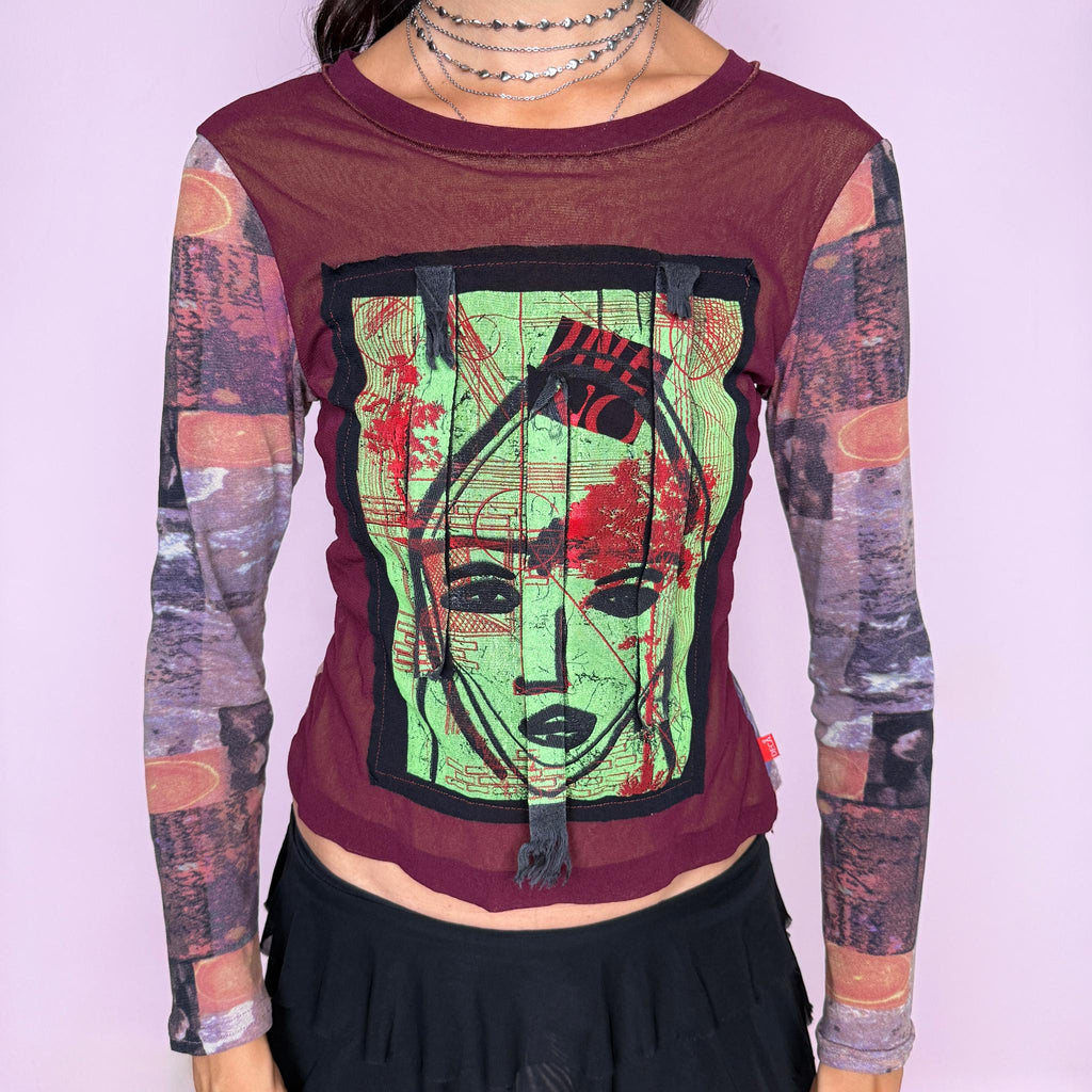 Vintage 2000s deconstructed graphic mesh top featuring a fitted burgundy body with contrasting printed long sleeves and a bold mixed-media face graphic appliqué at the front, finished with raw-edge fabric tabs and layered textile detailing. The combination of mesh, painterly print, and exposed appliqué construction gives it an art-to-wear, avant-garde aesthetic. From a French brand, made in France from stretchy 100% polyamide. Great vintage condition.