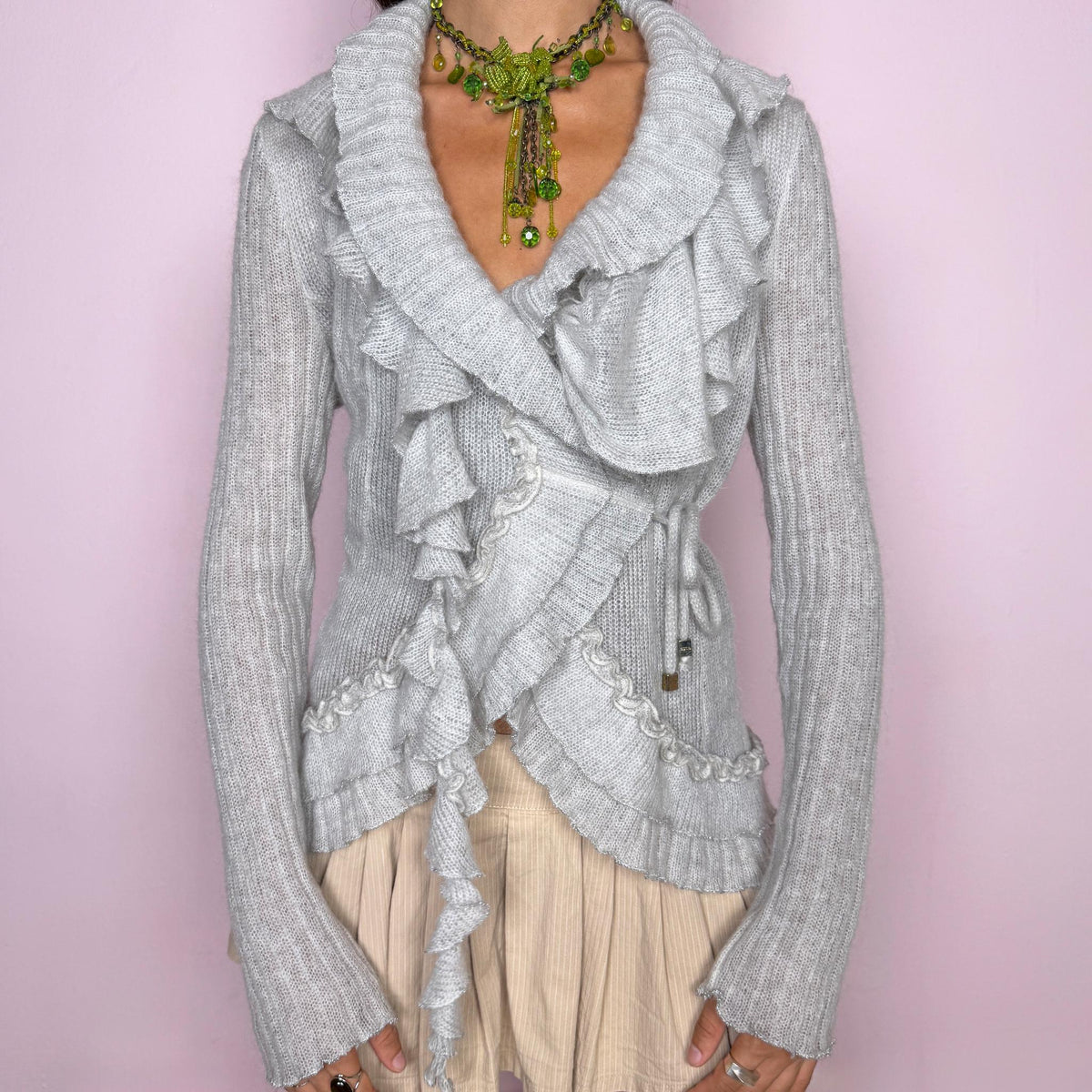 Vintage 2000s light gray wrap cardigan featuring a wrap-front silhouette with adjustable tie fastening, allowing the width and fit to be easily adjusted at the waist. Finished with cascading ruffle trim throughout, long sleeves and delicate textured knit detailing. The airy mohair blend, soft gray tone and sculptural ruffles give it a dreamy, romantic feel. By an Italian designer, made in Italy from a soft 20% mohair, 40% polyamide and 40% acrylic blend. Excellent vintage condition.
