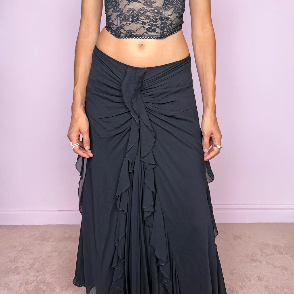 Vintage 2000s black silk midi skirt featuring soft ruching through the hips, cascading ruffle detailing down the front and sides, and a fluid flared hem for dramatic movement. Back zip closure and non-stretch. The layered silk construction and sculptural draping are ideal for elevated evening styling. Can be worn mid-rise for size M or lower on the waist for size S. Made in Italy by an Italian brand from 100% silk with a 100% polyester lining. Excellent vintage condition.