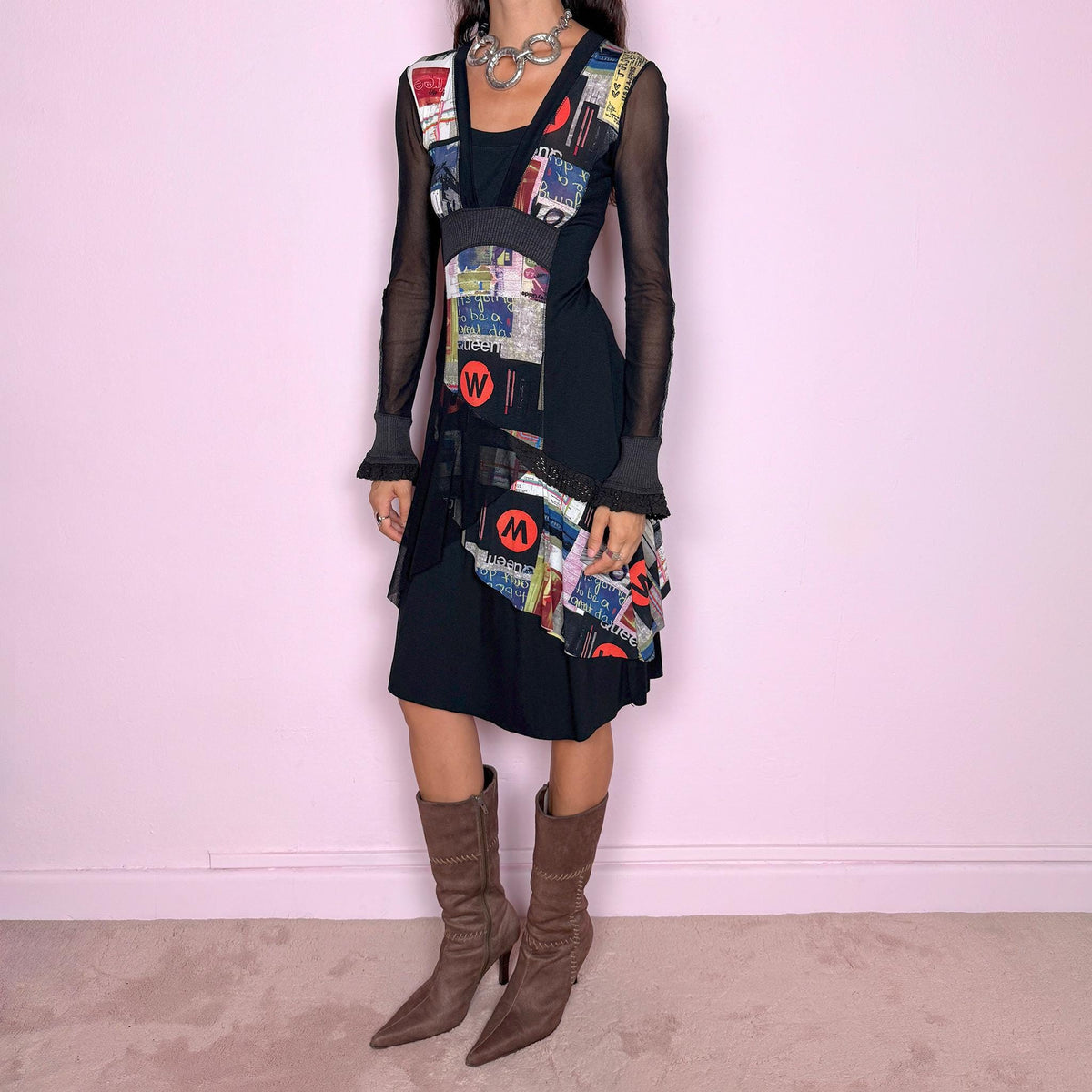 Vintage 2000s black midi dress featuring a stretchy fitted base with semi-sheer long sleeves and a layered deconstructed graphic construction through the front. Designed with an asymmetric mix of collage-style printed panels, text and bold multicolor motifs, plus contrasting ribbed sections and ruffled cuff details. The combination of sheer fabric, irregular paneling and graphic artwork gives it an avant-garde Y2K art-to-wear look.