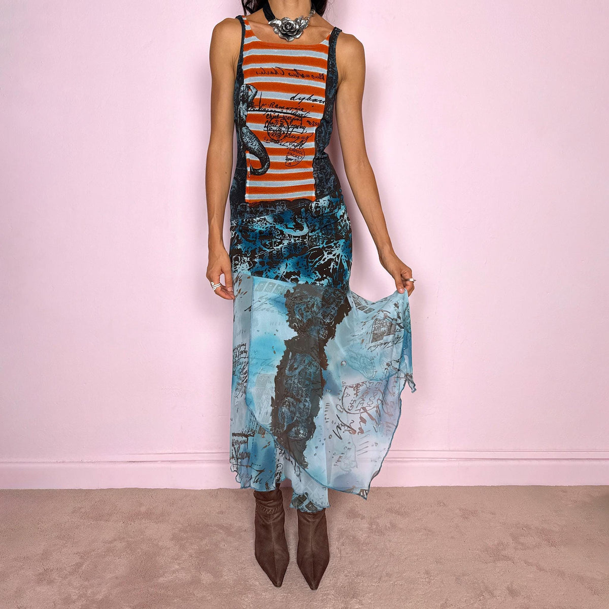 Vintage 2000s maximalist maxi dress featuring a mixed construction that combines fitted printed mesh through the upper body with semi-sheer mesh panels through the lower section, creating a fluid, layered effect. The graphic composition mixes striped, abstract, and handwritten-style motifs in burnt orange, brown, and vivid blue tones, finished with a dramatic asymmetric handkerchief hem for extra movement. A bold Y2K art-to-wear piece with an avant-garde, editorial feel.