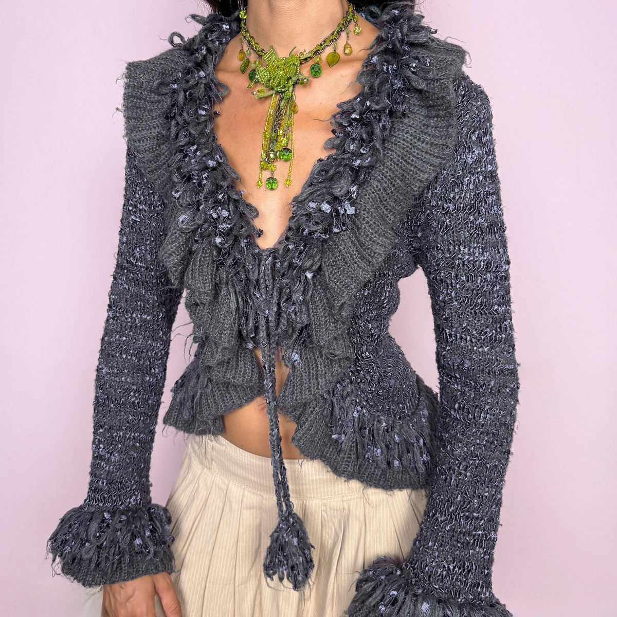 Vintage 2000s romantic gray tie-front cardigan crafted from a fuzzy 70% mohair, 20% acrylic, and 10% elastane blend. Featuring an adjustable tie fastening, dramatic textured fringe ruffle detailing along the neckline and hem, and long sleeves finished with ruffle cuffs. The brand label is missing. Excellent vintage condition.