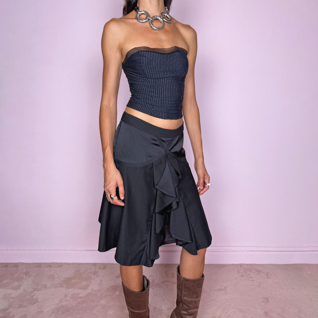 Vintage 2000s black pinstripe midi skirt featuring a side zip closure and sculptural layered panel construction with contrasting satin-like inserts and cascading asymmetric detailing through the front. Non-stretch. The mix of tailored pinstripes, curved seamwork, and deconstructed draping gives it a formal, dark avant-garde aesthetic. Can be worn mid-rise for size S or lower on the waist for size XS.