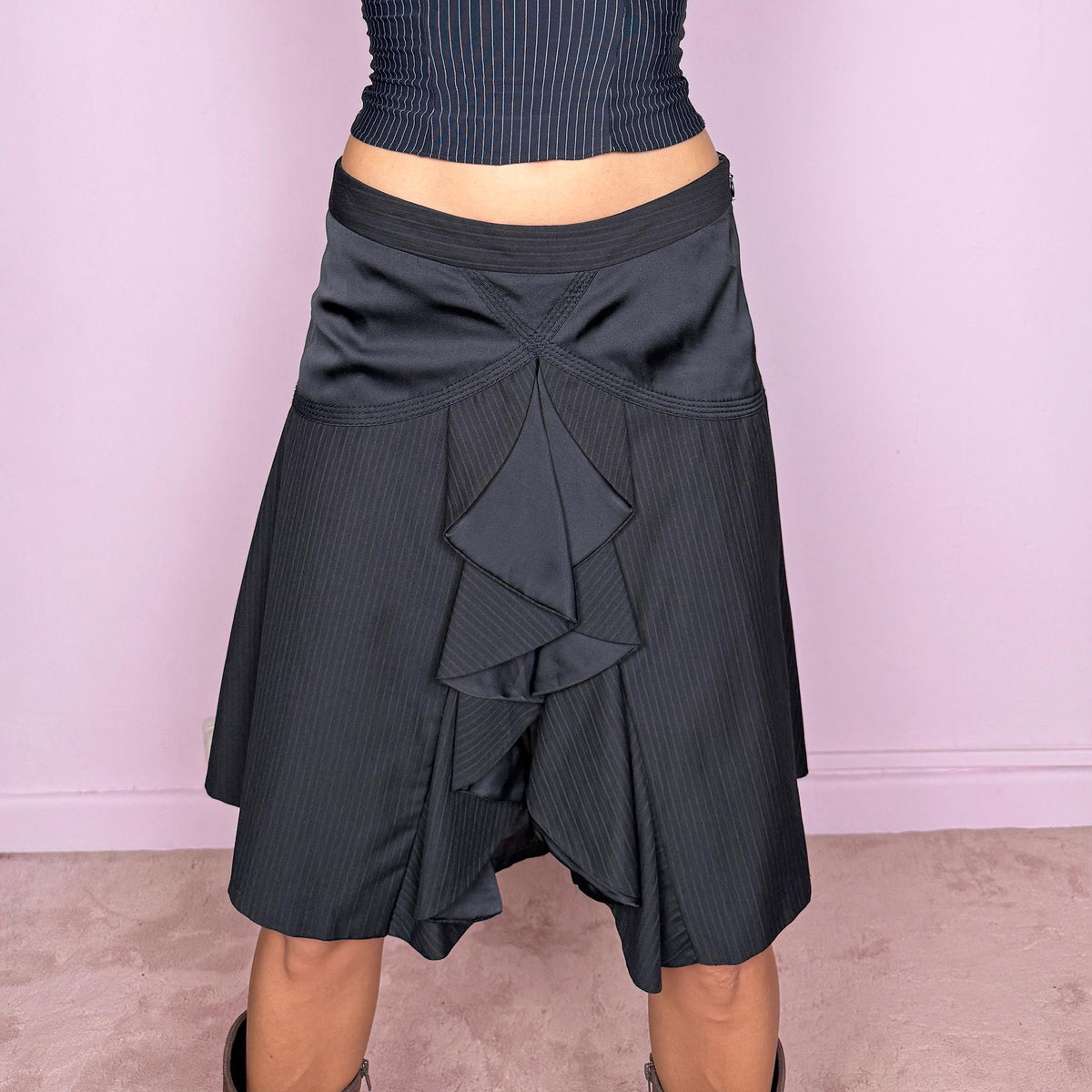 Vintage 2000s black pinstripe midi skirt featuring a side zip closure and sculptural layered panel construction with contrasting satin-like inserts and cascading asymmetric detailing through the front. Non-stretch. The mix of tailored pinstripes, curved seamwork, and deconstructed draping gives it a formal, dark avant-garde aesthetic. Can be worn mid-rise for size S or lower on the waist for size XS.