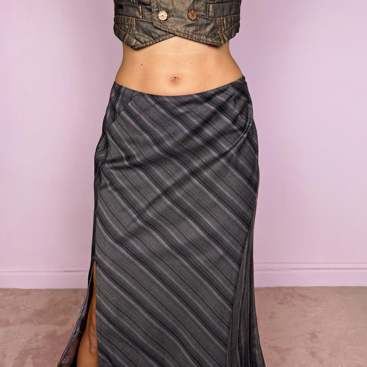 Vintage 2000s brownish-gray striped midi skirt by Kenzo Jungle, featuring diagonal stripe placement, a side slit, and a side zip closure. The muted brown-gray palette and refined tailoring give it a sophisticated, minimalist designer aesthetic. Can be worn mid-rise for size M. Crafted from a non-stretch blend of 58% viscose, 30% wool, 9% mohair, and 3% elastane, with a 100% polyester lining. Excellent vintage condition.