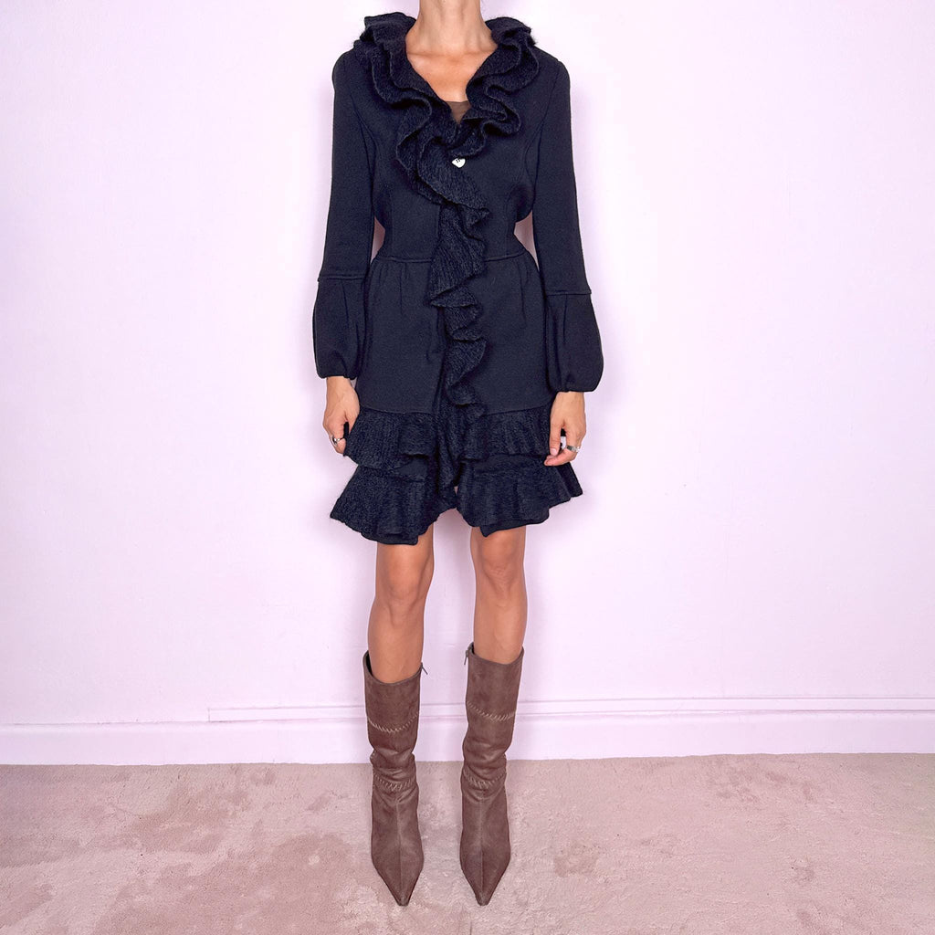 Vintage 2000s black wool coat, crafted from 100% wool with contrasting textured inserts in a blend of 50% mohair, 30% polyamide, and 20% wool. Featuring a fitted silhouette with dramatic ruffled trim through the neckline and front, voluminous sleeves, button closure, and pockets. Finished with a removable fabric belt that can be tied at the front or back to adjust the shape. From an Italian brand. Great vintage condition.