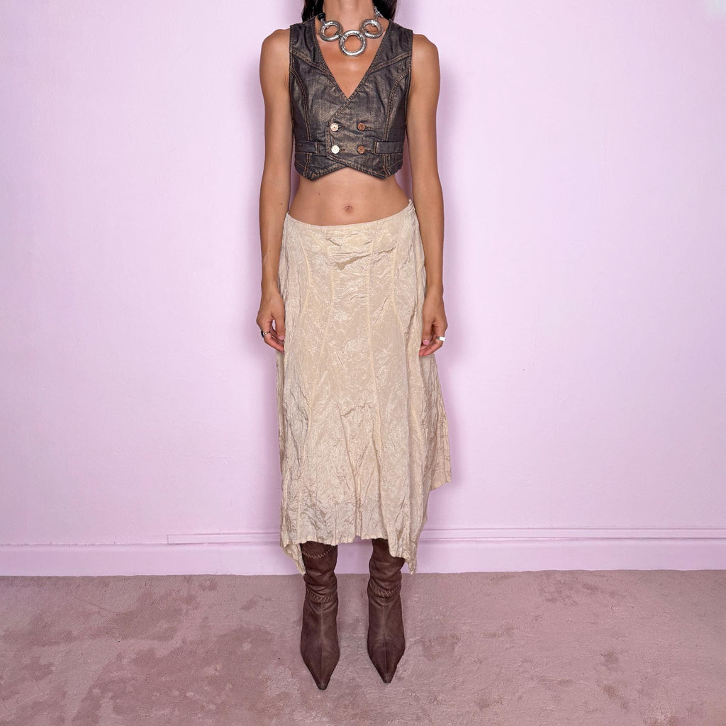 Vintage 2000s light cream-gold asymmetric midi skirt featuring a flared silhouette with an irregular handkerchief-style hem and a subtly crinkled, textured finish. Crafted from a structured, non-stretch blend of 53% polyamide, 32% cotton and 15% metallic fiber, with a 65% acetate and 35% viscose lining. Finished with a side zip closure. Can be worn mid-rise for size S or lower on the waist for size XS. From a German brand. Excellent vintage condition.