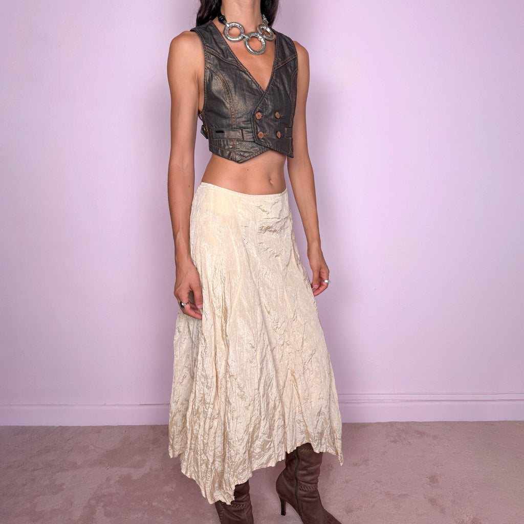 Vintage 2000s light cream-gold asymmetric midi skirt featuring a flared silhouette with an irregular handkerchief-style hem and a subtly crinkled, textured finish. Crafted from a structured, non-stretch blend of 53% polyamide, 32% cotton and 15% metallic fiber, with a 65% acetate and 35% viscose lining. Finished with a side zip closure. Can be worn mid-rise for size S or lower on the waist for size XS. From a German brand. Excellent vintage condition.