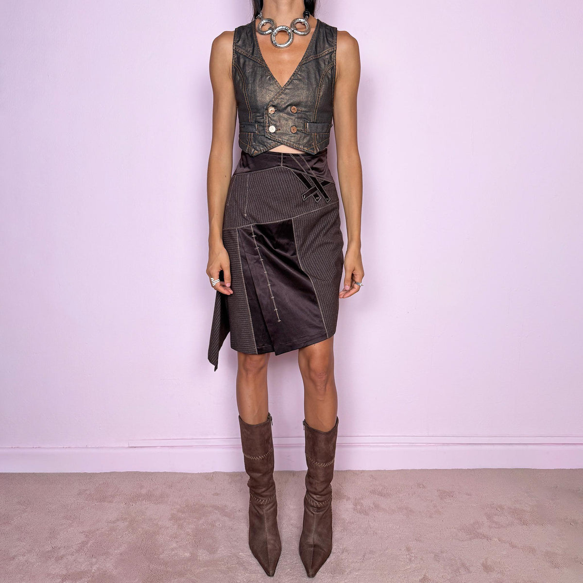 Vintage 2000s brown asymmetric midi skirt featuring a high-waisted, fitted silhouette with contrasting pinstripe and satin-like panels, sculptural draping along one side, and an elongated asymmetric hanging panel. Designed with contrast topstitching, decorative strap detailing, and a side zip closure. Non-stretch. The mix of tailored pinstripes, fluid draping, and deconstructed paneling gives it an avant-garde aesthetic. From a French brand.