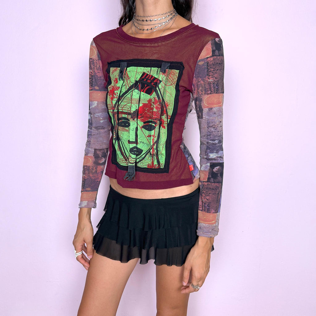 Vintage 2000s deconstructed graphic mesh top featuring a fitted burgundy body with contrasting printed long sleeves and a bold mixed-media face graphic appliqué at the front, finished with raw-edge fabric tabs and layered textile detailing. The combination of mesh, painterly print, and exposed appliqué construction gives it an art-to-wear, avant-garde aesthetic. From a French brand, made in France from stretchy 100% polyamide. Great vintage condition.