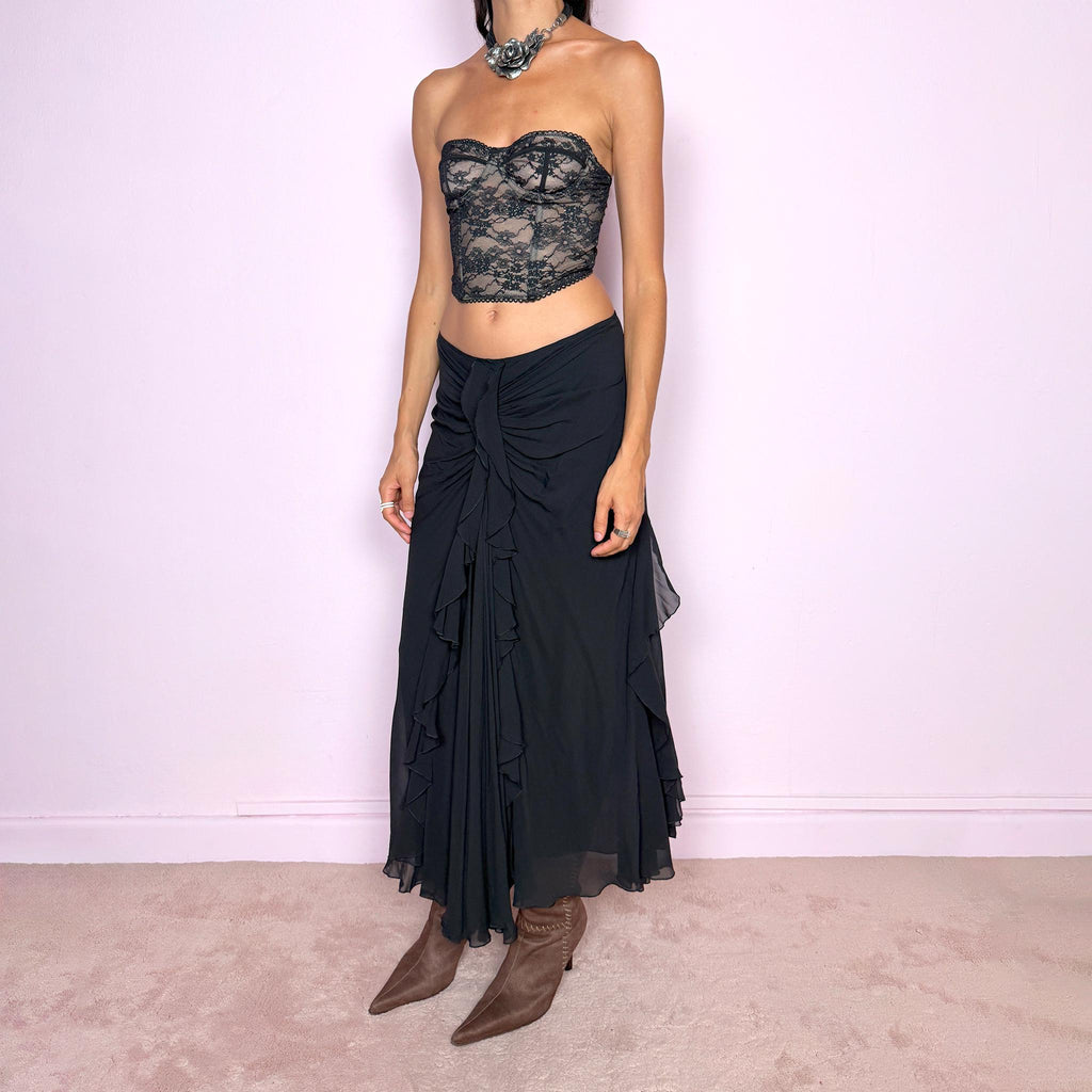 Vintage 2000s black silk midi skirt featuring soft ruching through the hips, cascading ruffle detailing down the front and sides, and a fluid flared hem for dramatic movement. Back zip closure and non-stretch. The layered silk construction and sculptural draping are ideal for elevated evening styling. Can be worn mid-rise for size M or lower on the waist for size S. Made in Italy by an Italian brand from 100% silk with a 100% polyester lining. Excellent vintage condition.