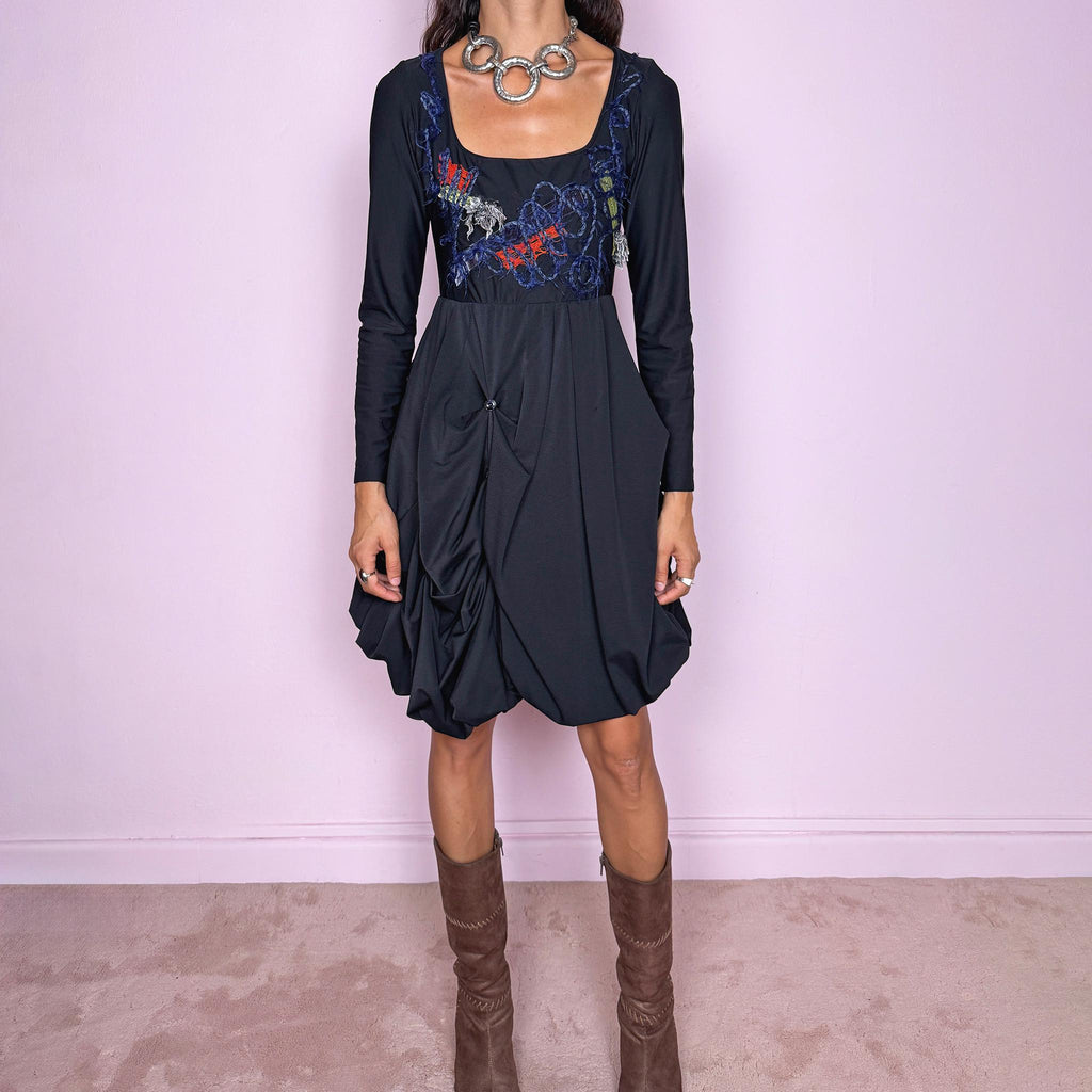 Vintage 2000s black long-sleeve mini dress by Italian label Save the Queen, made in Italy. Featuring a fitted stretchy bodice with a scoop neckline, layered textile appliqué detailing across the chest, and a sculptural draped bubble skirt with gathered volume and asymmetric folds. The sleek bodice and exaggerated balloon silhouette create an avant-garde, deconstructed look. Composition label is missing, so the exact fabric is unknown. Excellent vintage condition.
