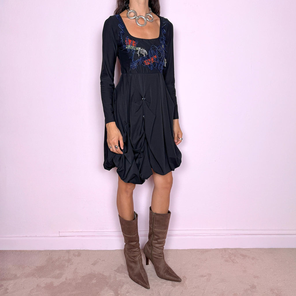 Vintage 2000s black long-sleeve mini dress by Italian label Save the Queen, made in Italy. Featuring a fitted stretchy bodice with a scoop neckline, layered textile appliqué detailing across the chest, and a sculptural draped bubble skirt with gathered volume and asymmetric folds. The sleek bodice and exaggerated balloon silhouette create an avant-garde, deconstructed look. Composition label is missing, so the exact fabric is unknown. Excellent vintage condition.