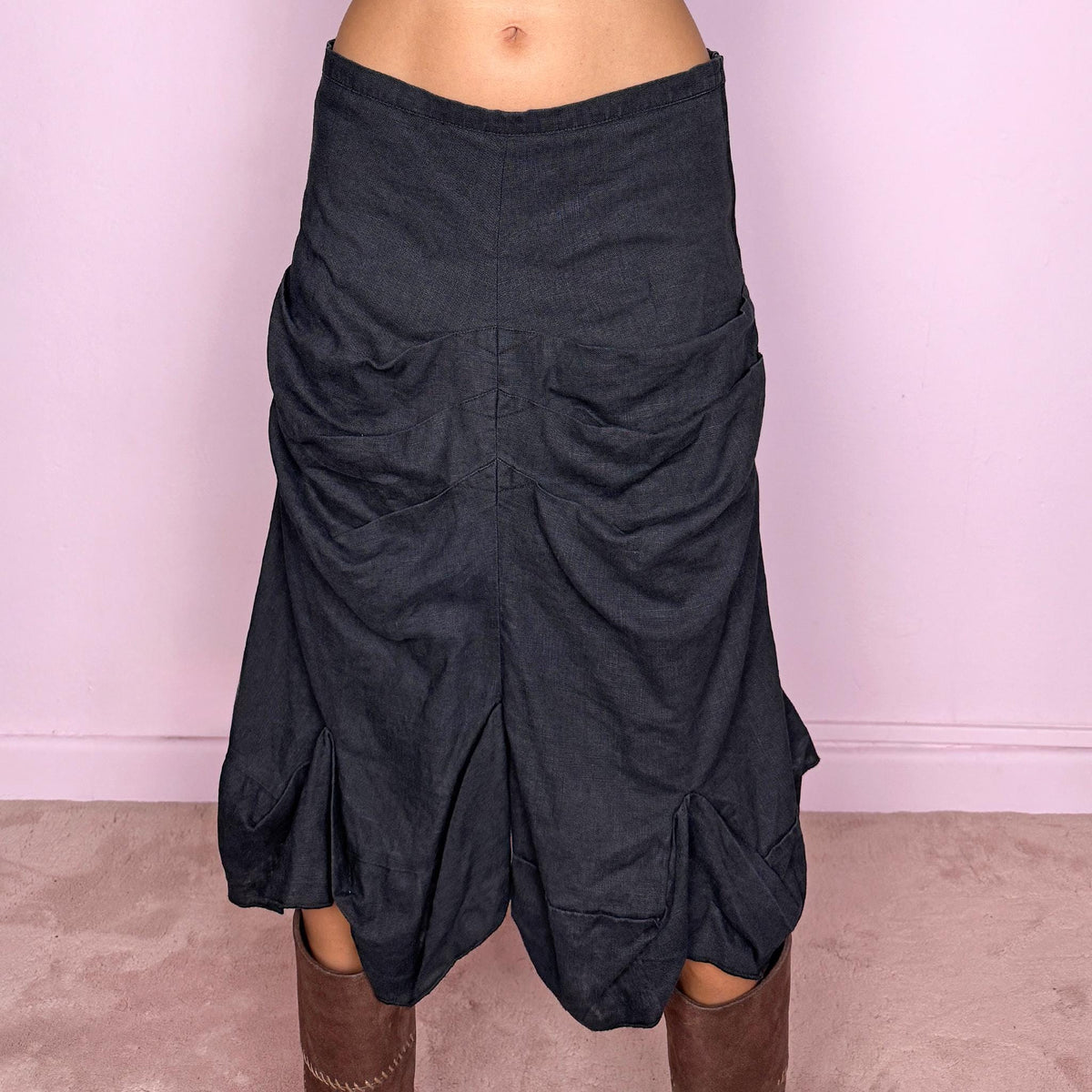 Vintage 2000s black linen midi skirt crafted from 100% linen. Featuring sculptural gathered draping through the front, curved panel construction and an irregular flared hem. The slightly faded black tone and natural linen texture give it a rustic, deconstructed avant-garde aesthetic. Non-stretch with 100% polyester lining. Can be worn mid-rise for size S or lower on the waist for size XS. From a Dutch brand. Excellent vintage condition.