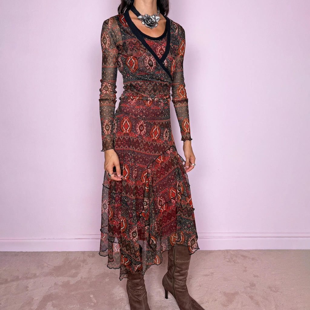 Vintage 2000s printed mesh two-piece dress set. The set includes a fitted sleeveless midi dress with a red lining and asymmetric layered hem, paired with a long-sleeve sheer mesh wrap top with tie fastening and contrasting black trim. Finished in an earthy red, burgundy, brown, and orange graphic print throughout. Perfect for layered bohemian styling. From a French brand, made in France from stretchy 100% polyester. Great vintage condition.
