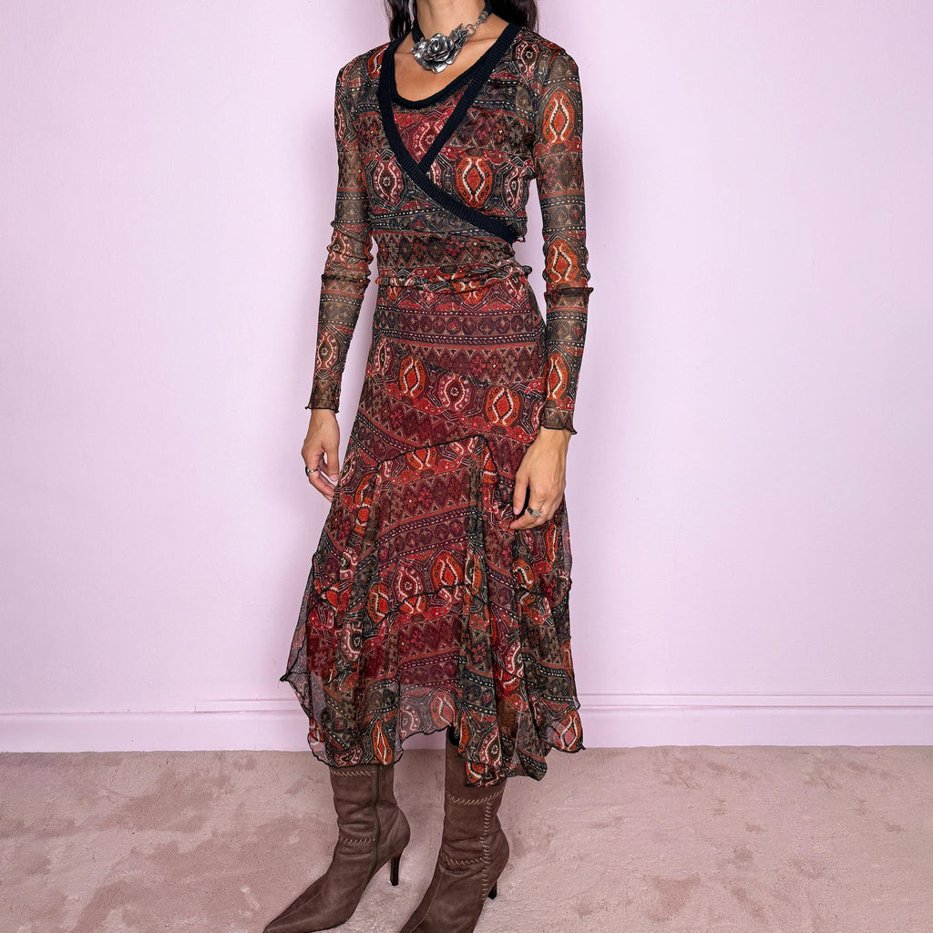 Vintage 2000s printed mesh two-piece dress set. The set includes a fitted sleeveless midi dress with a red lining and asymmetric layered hem, paired with a long-sleeve sheer mesh wrap top with tie fastening and contrasting black trim. Finished in an earthy red, burgundy, brown, and orange graphic print throughout. Perfect for layered bohemian styling. From a French brand, made in France from stretchy 100% polyester. Great vintage condition.