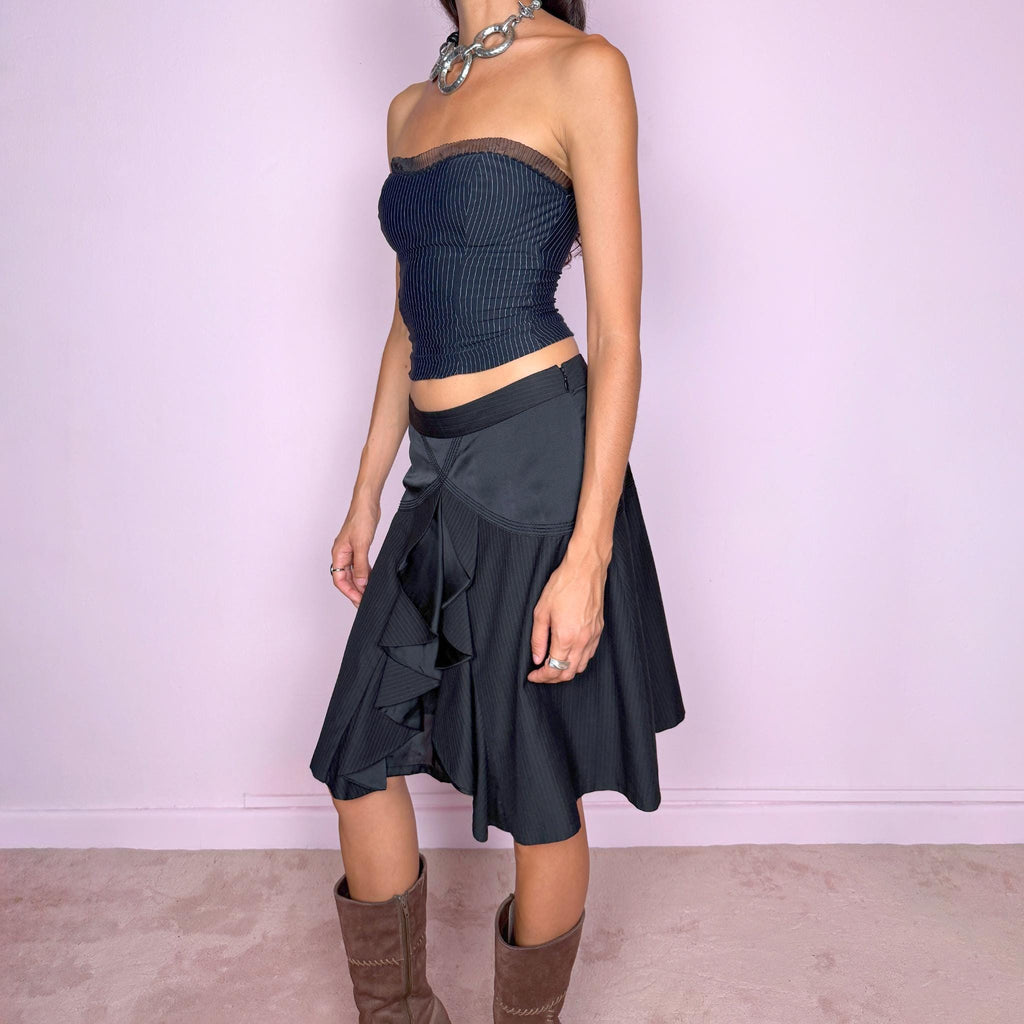 Vintage 2000s black pinstripe midi skirt featuring a side zip closure and sculptural layered panel construction with contrasting satin-like inserts and cascading asymmetric detailing through the front. Non-stretch. The mix of tailored pinstripes, curved seamwork, and deconstructed draping gives it a formal, dark avant-garde aesthetic. Can be worn mid-rise for size S or lower on the waist for size XS.
