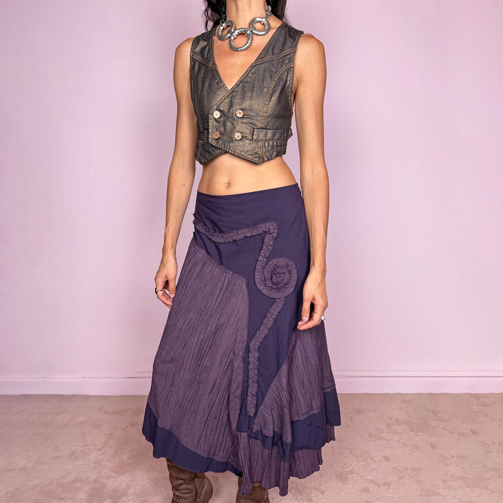 Vintage 2000s dark purple asymmetric midi skirt from a French brand, made in France. Features an irregular layered silhouette with contrasting pleated panels, curved seam construction, sculptural ruffled appliqué detailing, and a layered hem. Finished with a side zip closure. Can be worn high-waisted for size L or lower on the waist for sizes M–S.