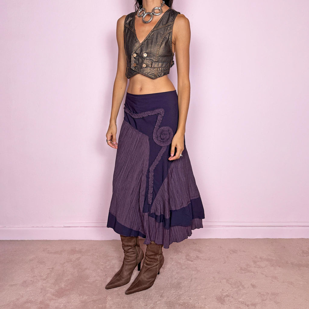 Vintage 2000s dark purple asymmetric midi skirt from a French brand, made in France. Features an irregular layered silhouette with contrasting pleated panels, curved seam construction, sculptural ruffled appliqué detailing, and a layered hem. Finished with a side zip closure. Can be worn high-waisted for size L or lower on the waist for sizes M–S.
