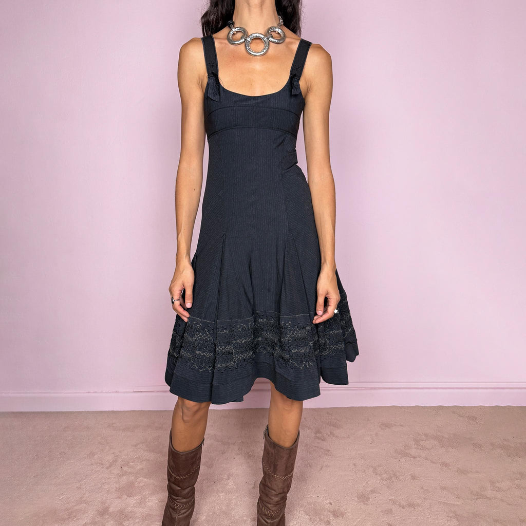 Vintage 2000s black midi dress by French label Marithé + François Girbaud, featuring a fitted sleeveless bodice with a scoop neckline and curved seam construction through the torso. The fabric has a subtle micro-pinstripe texture, while the silhouette flares from the hips into a structured A-line skirt with embroidered details. Made from a stretchy blend of 72% polyamide and 28% elastane. Excellent vintage condition.