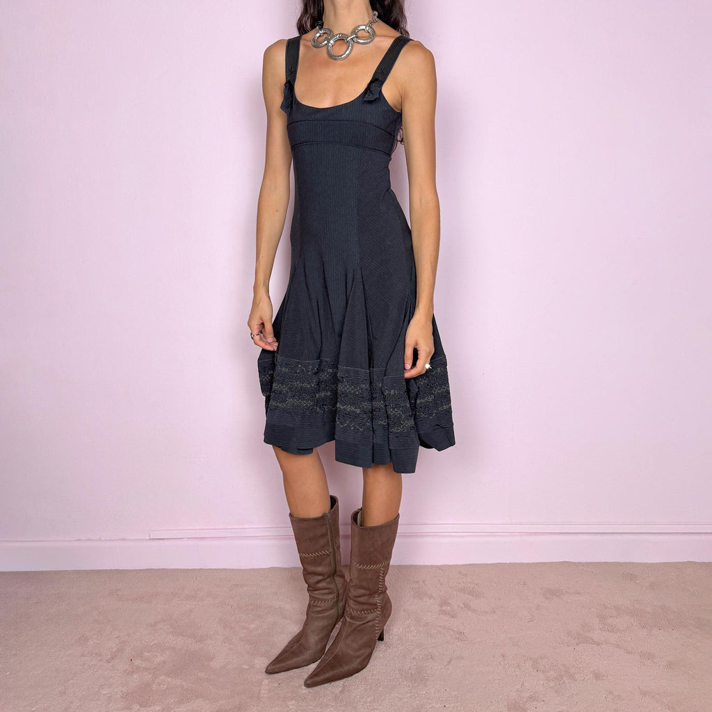 Vintage 2000s black midi dress by French label Marithé + François Girbaud, featuring a fitted sleeveless bodice with a scoop neckline and curved seam construction through the torso. The fabric has a subtle micro-pinstripe texture, while the silhouette flares from the hips into a structured A-line skirt with embroidered details. Made from a stretchy blend of 72% polyamide and 28% elastane. Excellent vintage condition.