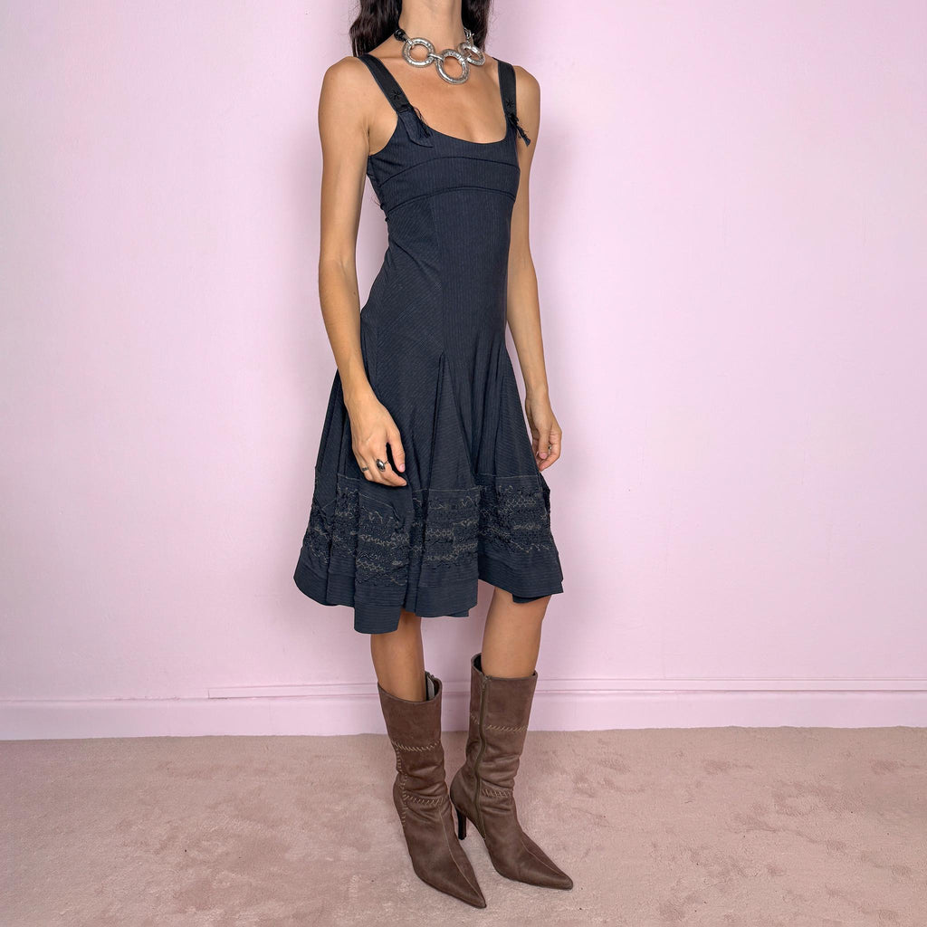 Vintage 2000s black midi dress by French label Marithé + François Girbaud, featuring a fitted sleeveless bodice with a scoop neckline and curved seam construction through the torso. The fabric has a subtle micro-pinstripe texture, while the silhouette flares from the hips into a structured A-line skirt with embroidered details. Made from a stretchy blend of 72% polyamide and 28% elastane. Excellent vintage condition.