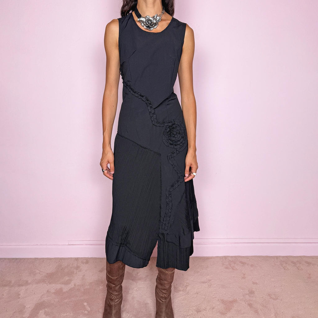 Vintage 2000s black asymmetric midi dress featuring a sleeveless silhouette with sculptural panel construction, mixed tonal textures, and ruffled trim creating an organic, deconstructed effect across the body. Finished with an irregular asymmetric hem and back zip closure. No stretch. For dark avant-garde looks. Made in France by a French brand. Main fabric: 61% viscose and 39% polyester. Other fabric: 54% cotton and 46% polyamide. Excellent vintage condition.