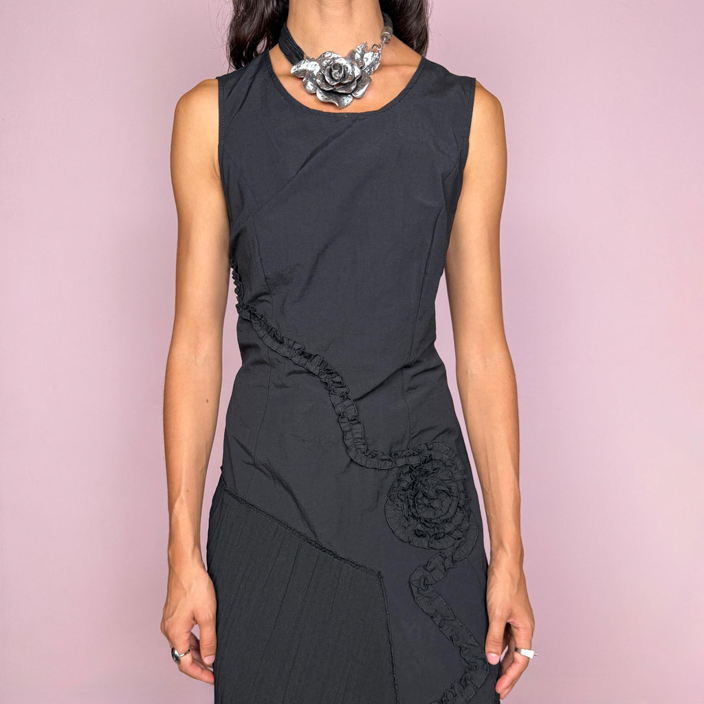 Vintage 2000s black asymmetric midi dress featuring a sleeveless silhouette with sculptural panel construction, mixed tonal textures, and ruffled trim creating an organic, deconstructed effect across the body. Finished with an irregular asymmetric hem and back zip closure. No stretch. For dark avant-garde looks. Made in France by a French brand. Main fabric: 61% viscose and 39% polyester. Other fabric: 54% cotton and 46% polyamide. Excellent vintage condition.