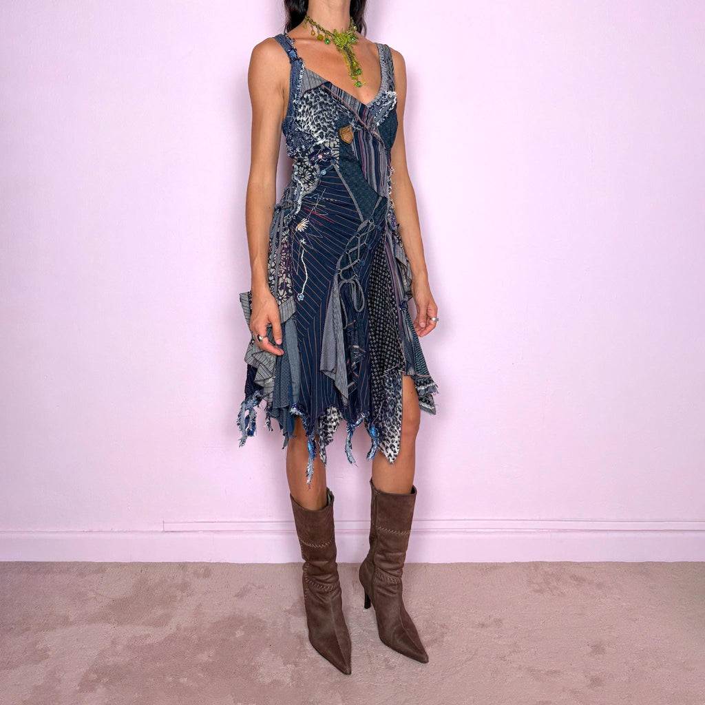 Vintage 2000s dark blue patchwork midi dress featuring an intricate deconstructed construction made from mixed pinstripe, floral, animal-print, and textured fabric panels. Designed with a deep V-neckline, fitted bodice, asymmetric layered skirt, exposed seams, raw-edge finishes, decorative stitching, lace-up detailing, and multiple draped panels throughout. Finished with a side zip closure. Non-stretch. For ragged-doll, bohemian, and avant-garde looks.