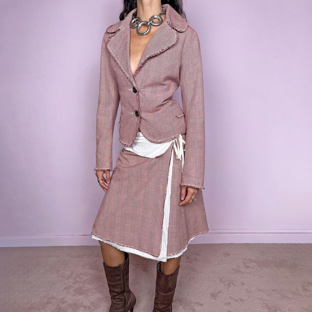 Vintage 2000s burgundy-red and cream two-piece skirt suit. The set includes a fitted blazer with a glen plaid / Prince of Wales check pattern, raw-edge trim, notched lapels, and a two-button front closure. Paired with a matching wrap-style midi skirt featuring layered cream lining, a side button closure, and an adjustable tie. The contrasting construction and unfinished edges create a relaxed, deconstructed feel while maintaining a tailored silhouette.