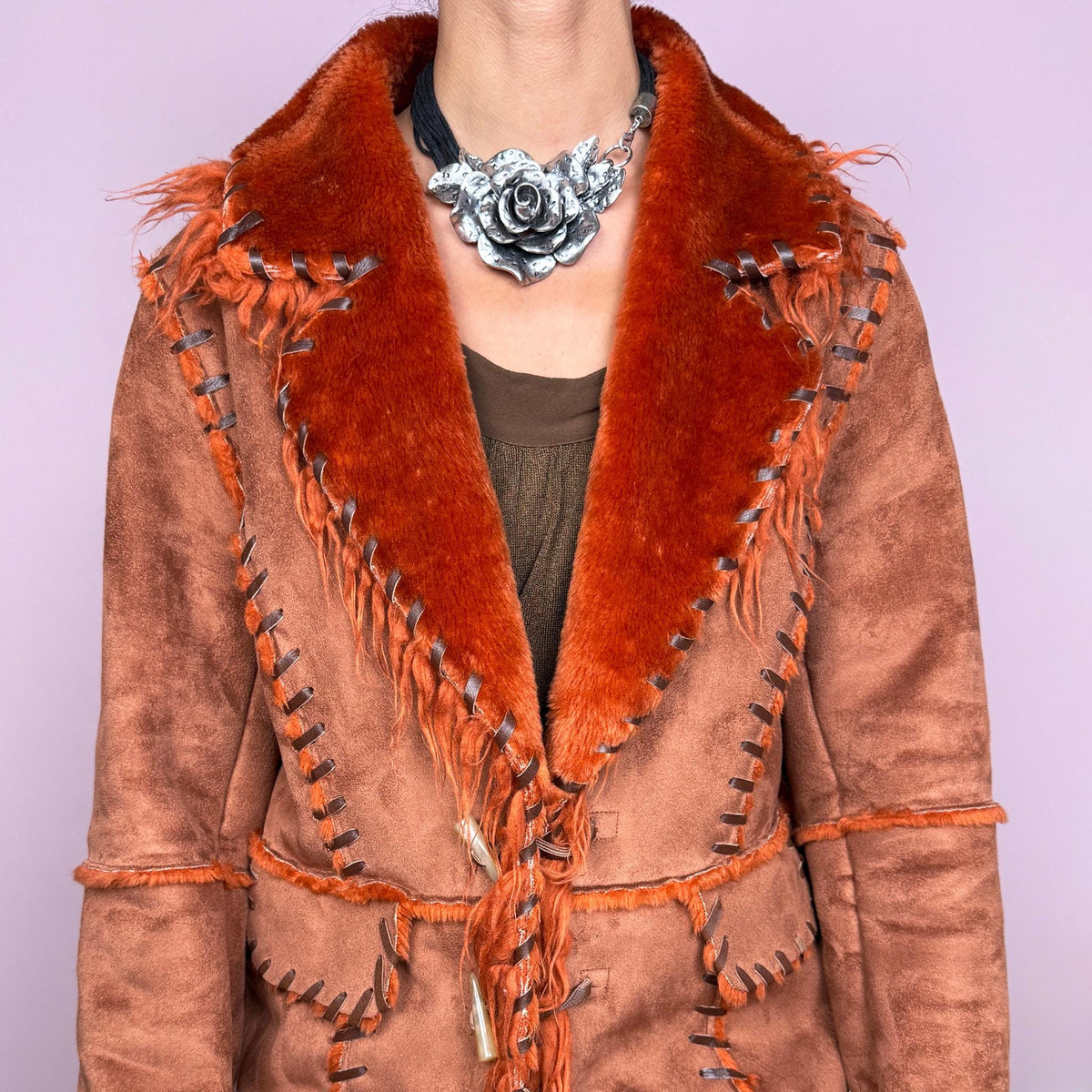 Vintage 2000s rusty terracotta faux-suede coat featuring rich burnt-orange faux-fur trim along the oversized collar and cuffs. Designed with contrast whipstitch detailing throughout, front patch pockets, and toggle-style closures with braided ties down the front. Features a 70s-inspired Penny Lane Y2K aesthetic. The labels are missing, so the exact fabric is unknown. Excellent vintage condition.