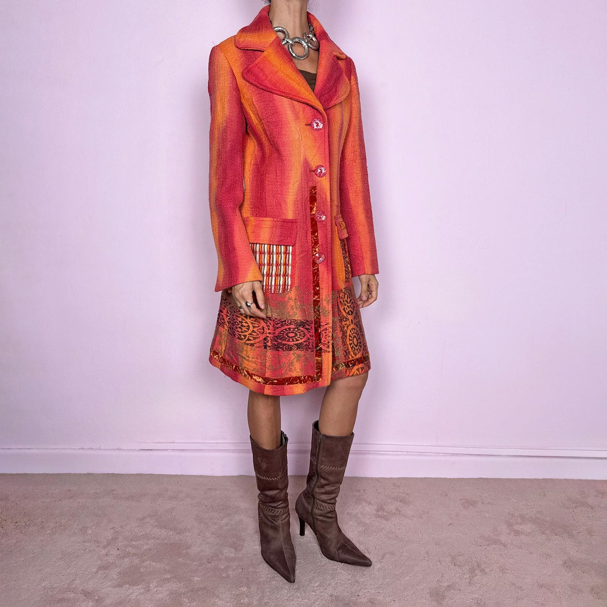 Vintage 2000s statement coat by Italian label Save the Queen, made in Italy from 100% virgin wool. Features a fitted longline silhouette in vivid coral, orange and red tones, with oversized notched lapels, decorative front buttons and contrasting mixed-media patch pockets. The lower section is finished with richly patterned jacquard-style panels, metallic accents and ornamental motifs, creating a highly detailed maximalist construction. Excellent vintage condition.