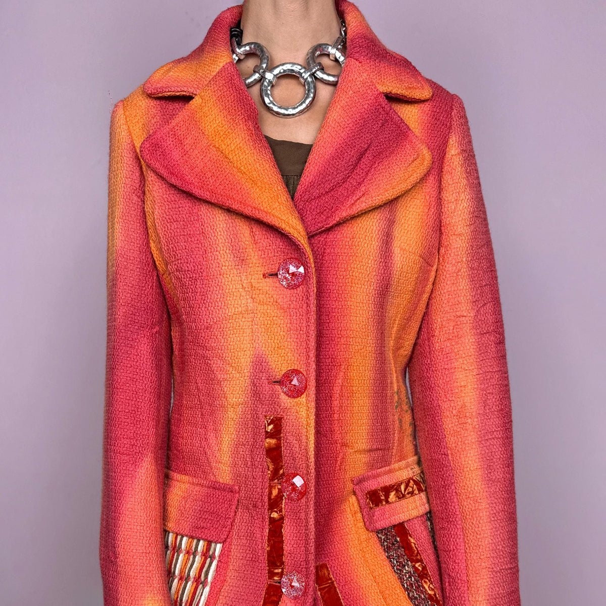 Vintage 2000s statement coat by Italian label Save the Queen, made in Italy from 100% virgin wool. Features a fitted longline silhouette in vivid coral, orange and red tones, with oversized notched lapels, decorative front buttons and contrasting mixed-media patch pockets. The lower section is finished with richly patterned jacquard-style panels, metallic accents and ornamental motifs, creating a highly detailed maximalist construction. Excellent vintage condition.