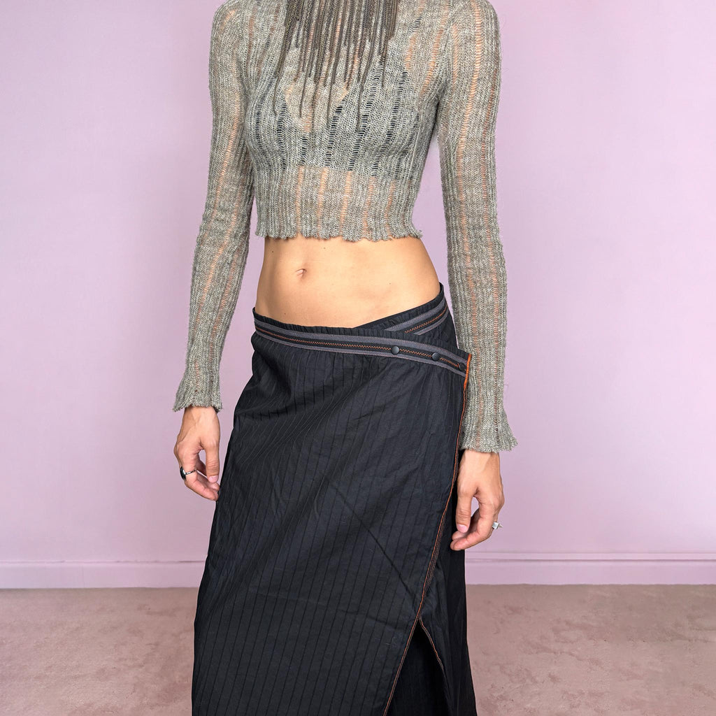 Vintage 2000s black midi skirt by French label Cop Copine, made from 100% cotton with no stretch. Features an asymmetric wrap-style construction, subtle vertical stripe texture, snap-button fastening at the waist, and a dramatic side slit with contrast topstitching. Finished with layered panel detailing for a deconstructed, utilitarian, dark avant-garde look. Can be worn mid-rise for size M or lower on the waist for size S. Excellent vintage condition.