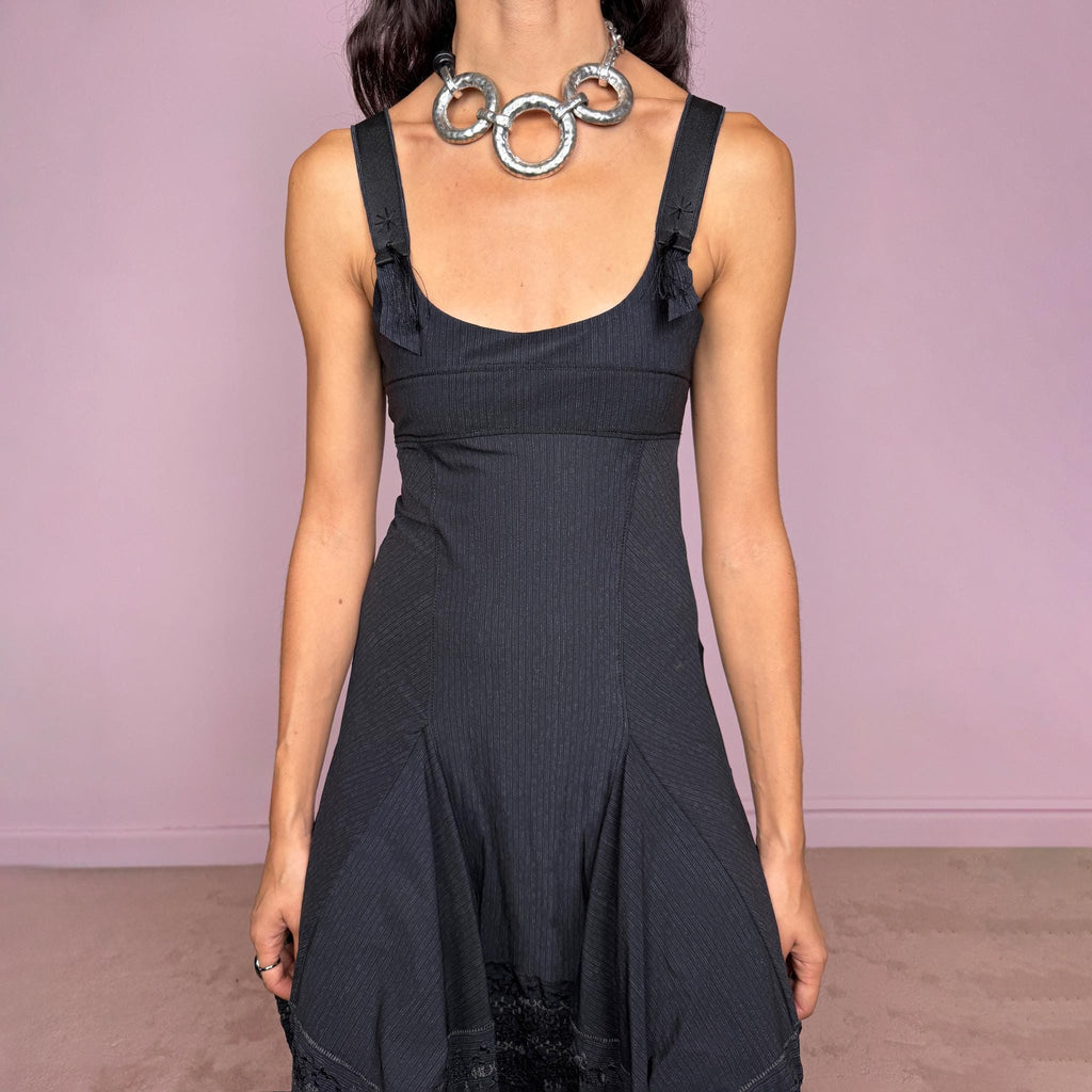 Vintage 2000s black midi dress by French label Marithé + François Girbaud, featuring a fitted sleeveless bodice with a scoop neckline and curved seam construction through the torso. The fabric has a subtle micro-pinstripe texture, while the silhouette flares from the hips into a structured A-line skirt with embroidered details. Made from a stretchy blend of 72% polyamide and 28% elastane. Excellent vintage condition.