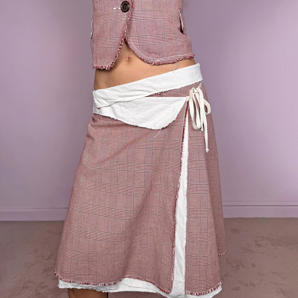 Vintage 2000s burgundy-red and cream two-piece skirt suit. The set includes a fitted blazer with a glen plaid / Prince of Wales check pattern, raw-edge trim, notched lapels, and a two-button front closure. Paired with a matching wrap-style midi skirt featuring layered cream lining, a side button closure, and an adjustable tie. The contrasting construction and unfinished edges create a relaxed, deconstructed feel while maintaining a tailored silhouette.