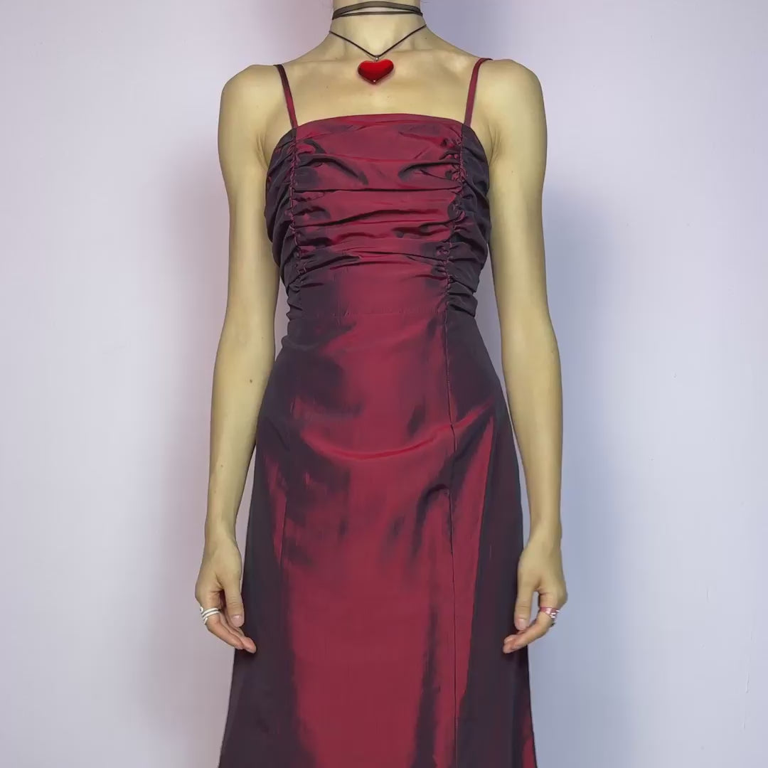 The Vintage 90s Burgundy Ruched Maxi Dress is a show-stopping piece featuring a rich burgundy tone with a lustrous satin-style finish. The ruched bodice adds texture and dimension, while the fitted silhouette flows into a soft A-line skirt. Designed with dainty spaghetti straps, a maxi length for dramatic flair, and a hidden side zipper closure for a seamless fit. Perfect for prom, formal events, or romantic night-outs. Excellent vintage condition.