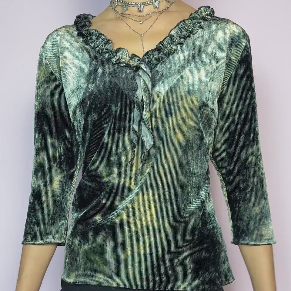 The Y2K Velvet Ruffle Top is a vintage 2000s tie-dye blouse featuring a luxurious ribbed velvet texture in dark olive-gray, beige, and ash tones. Designed with a romantic ruffled neckline and elegant three-quarter sleeves. The ribbed velvet catches the light beautifully, giving off a soft shimmer that makes it perfect for witchy autumn looks, fairy grunge layering, or going-out outfits. Soft, stretchy, and unique — a true statement piece. Ideal for dark romance, gothic glam, or evening wear aesthetics.
