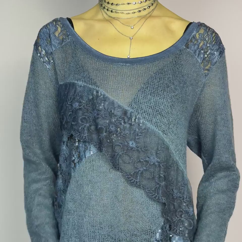 The Y2K Blue Lace Asymmetric Sweater is a vintage 2000s piece featuring a semi-sheer knit design with delicate lace and sequin paneling in an asymmetrical pattern. Designed with a scoop neckline, long sleeves, and a flowy silhouette, this sweater tunic adds a dreamy, romantic touch to any outfit. Perfect for layering in autumn and winter.