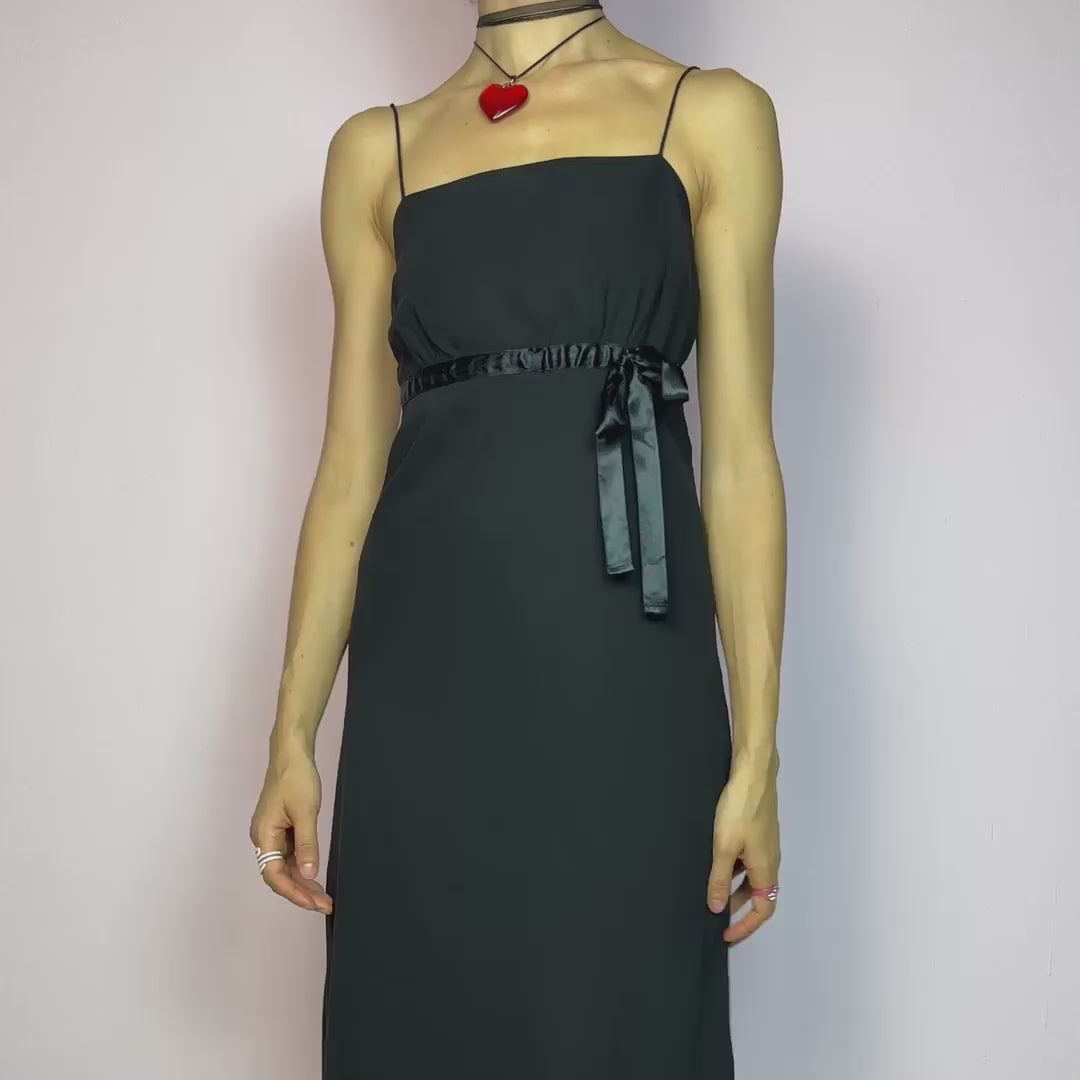 The Y2K Black Slip Midi Dress is a vintage 2000s dreamy minimalist piece featuring a lightweight sheer overlay, spaghetti straps, a flattering empire waist with a satin tie, and a classic midi silhouette. The lightweight, flowy fabric creates beautiful movement, making it perfect for party looks and romantic evenings. Classic, versatile, and effortlessly chic. Great vintage condition.
