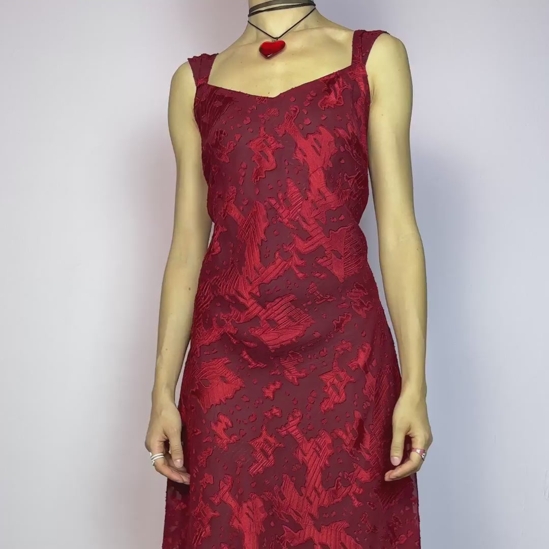 The Vintage 90s Maroon Textured Midi Dress is a romantic and striking piece in a rich maroon tone with abstract textured patterns and a sheer overlay. Designed with wide straps, a flattering sweetheart neckline, and a flowy midi-length cut. The semi-sheer fabric adds depth while the inner lining provides comfort. Perfect for formal events, romantic nights, or gothic glam looks. Elegant, timeless, and effortlessly dramatic. Excellent vintage condition.