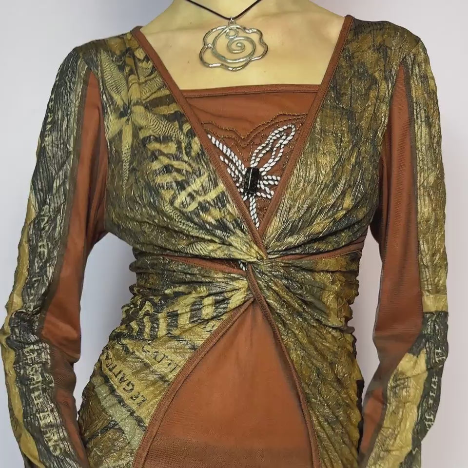 The Y2K Brown Mesh Overlay Top is a vintage 2000s long sleeve designed by Legatte Jeans. Crafted in a moody mix of orange, brown, and bronze tones, it features a twisted front detail and a combination of stretchy mesh and jersey fabrics. A subtle embroidered flower motif decorates the chest, adding a delicate accent to the bold, structured silhouette. With its sculptural cut and sheer elements, this top is perfect for cyber aesthetics, artsy fashion, and Y2K clubwear. Made in Italy. Excellent vintage condit