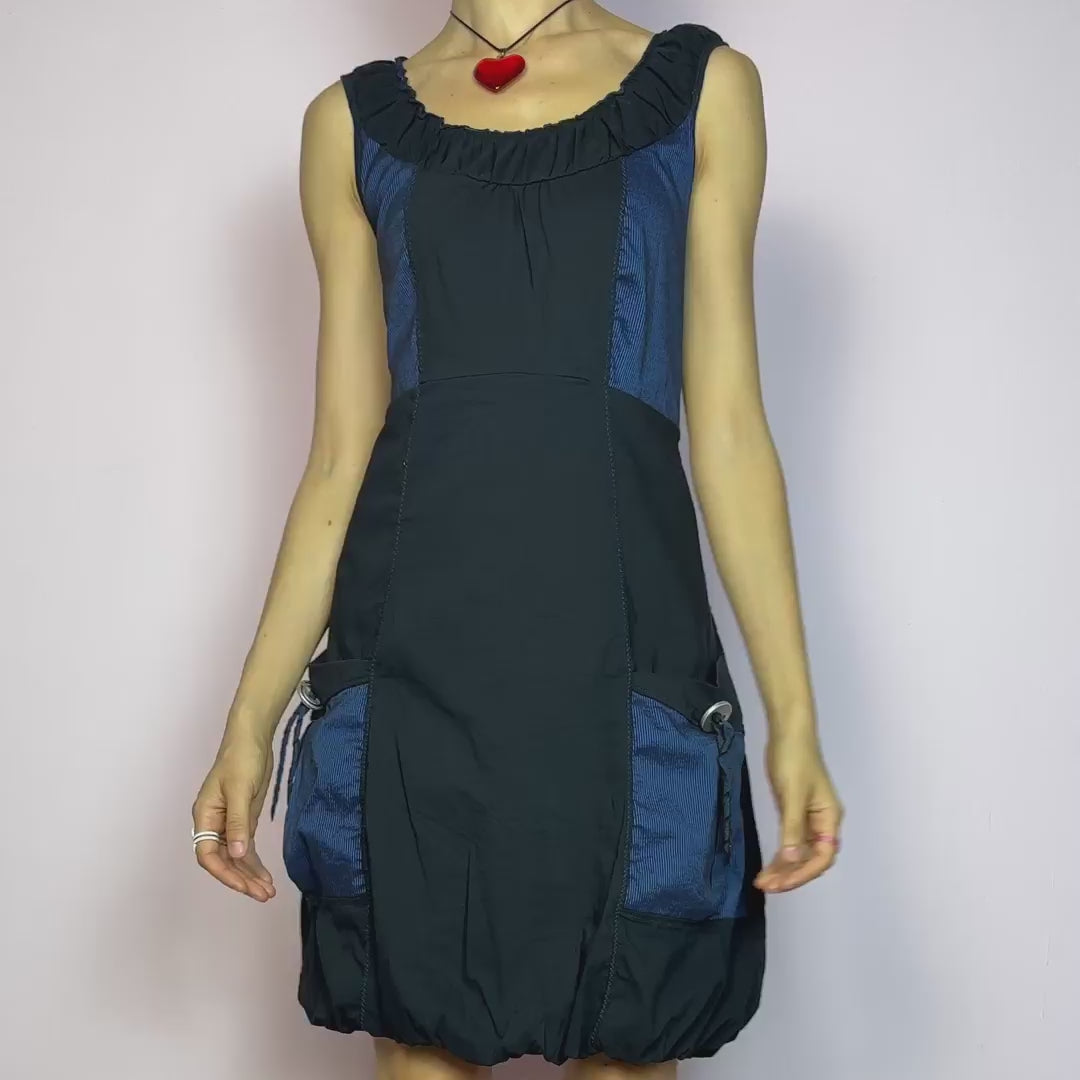 The Y2K Navy &amp; Black Bubble Mini Dress is a bold vintage 2000s statement piece with utility-inspired vibes. Features a unique bubble hem, ruched scoop neckline, and structured paneled design with contrast navy inserts. Equipped with chunky side pockets and metal ring details for an industrial touch. Made from a stretchy fabric with a techy texture. Perfect for dystopian streetwear, cyber grunge, or Harajuku styling. Great vintage condition.