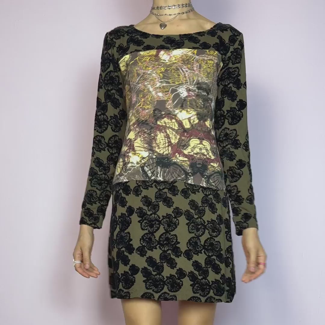 The Y2K Printed Velvet Mini Dress is a striking and artsy vintage piece from the 2000s. This stretchy mini dress features a unique mixed-media design with an abstract print panel at the chest, contrasted by a brown base covered in bold black velvet flocked florals. With its long sleeves, slightly flared hem, and figure-hugging silhouette, it's perfect for maximalist layering or making a statement on its own. A rare cyber-romantic gem for experimental, alt, or fairy-grunge wardrobes. Excellent vintage condit