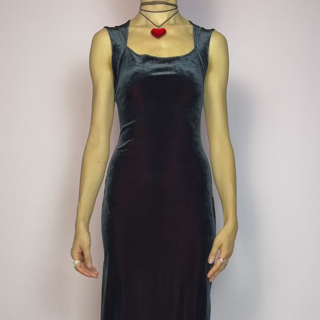 The Vintage 90s Black Velvet Midi Dress is pure elegance with a twist. Crafted from deep black velvet with a maroon undertone, it catches the light with rich, dark burgundy reflections that give it a luxe finish. Features wide straps, a square neckline, and a body-hugging midi silhouette that flatters and elongates. Soft and stretchy for comfort, yet bold and dramatic for gothic, romantic, or night-out looks. A subtly striking piece that stands out in movement and moonlight. Made in Europe.