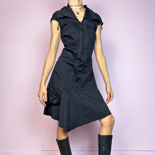 This vintage 2000s black techwear dress features cap sleeves, a dramatic asymmetric hem, and sculptural paneling for a bold silhouette. Made from a stretchy fabric, it includes a side zip closure and ruched utility pocket. Decorative topstitching and a funnel-style collar with drawstrings elevate the structure. Mid-length and lightweight, perfect for summer. A sleek statement in futuristic edge. Great vintage condition.