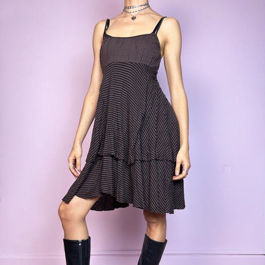 This vintage 2000s brown midi dress features a fine black stripe pattern, square neckline, and thin shoulder straps. Made from a soft, stretchy knit, it has an empire waist and a tiered asymmetric hem that drapes with ease. Perfect for summer. A casual, fairy grunge–inspired piece with subtle volume and flow—blending comfort, minimalism, and quiet edge. Great vintage condition.